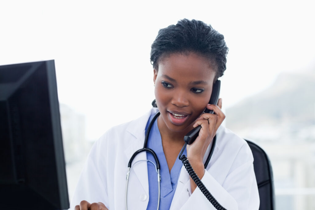 Female doctor on the phone while using a computer in her office. 9 Telephone Triage Red Flags