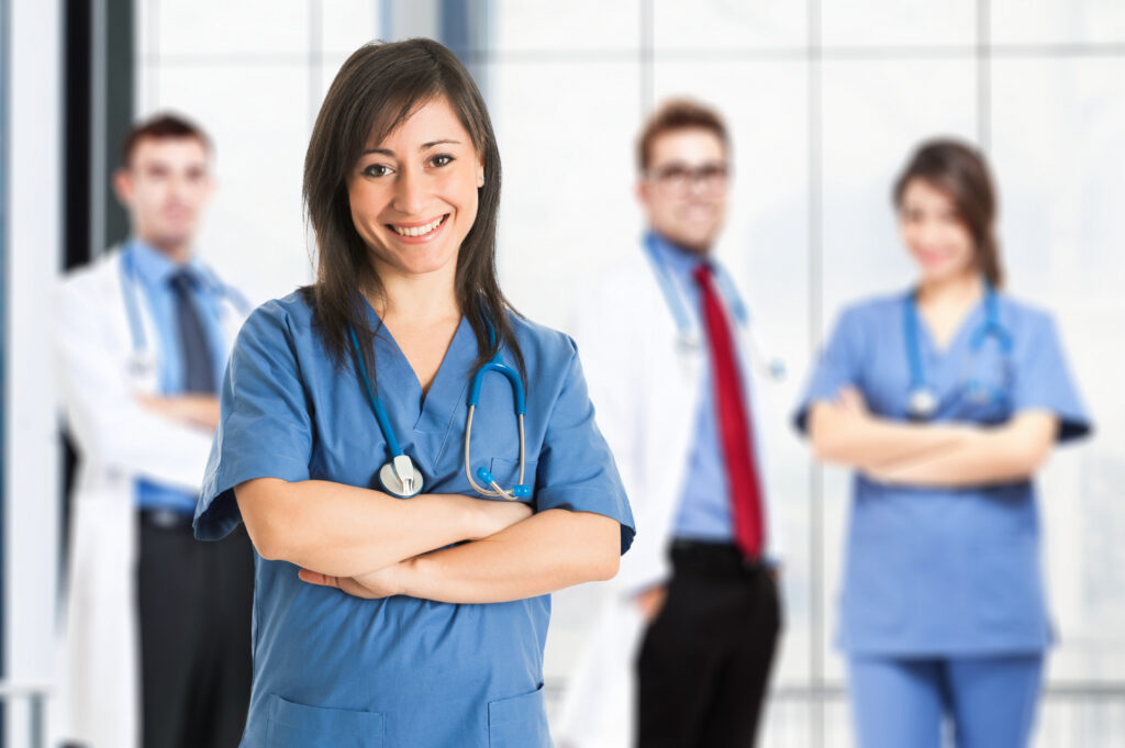 Portrait of a smiling nurse in front of her medical team. Questions About Triage Nurses