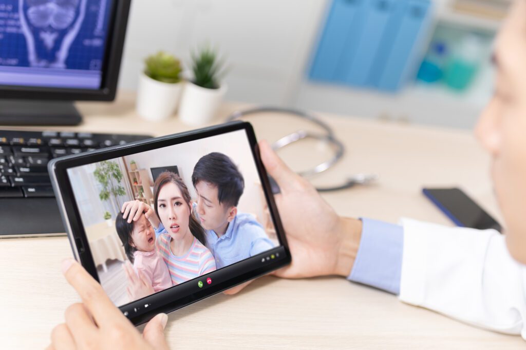 Telemedicine concept - back view of asian male pediatrician is listening to the family on digital tablet. Triage Success Stories