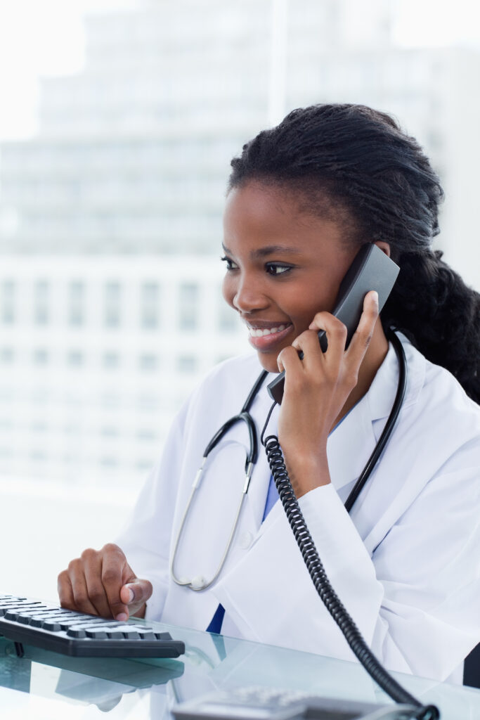 Portrait of a female doctor on the phone while using a computer in her office. Triage Nursing Skill